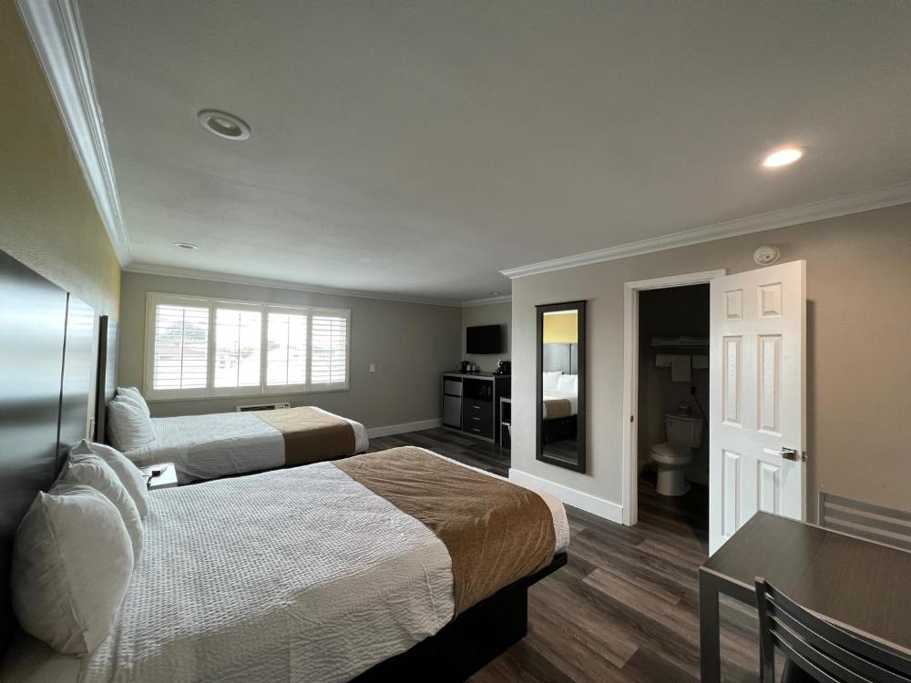 King bed guest room with fresh white linens at Deluxe Inn Hawthorne, Hawthorne CA hotel near LAX